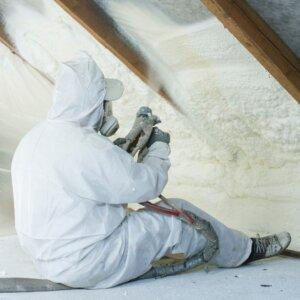 Technician applying spray foam to an attic ceiling