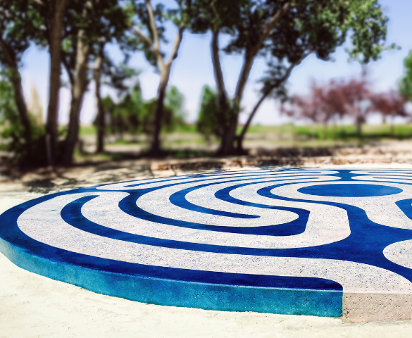 a photo of a rounded concrete flooring structure with a blue dyed swirl pattern in an outdoor park