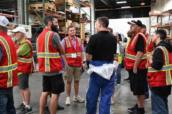 group in the warehouse image of a group of people wearing safety gear talking together inside a warehouse