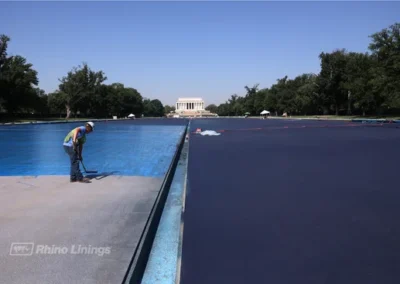 close-up-of-contractor-spreading-blue-epoxy-protective-coatings-across-reflecting-pool-Lincoln-Memorial-in-distance